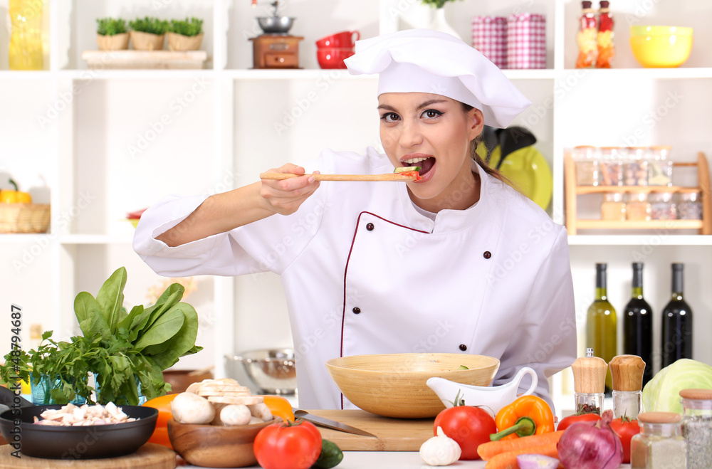 Young woman chef cooking in kitchen
