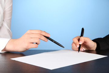 Two business partners signing document, on blue background