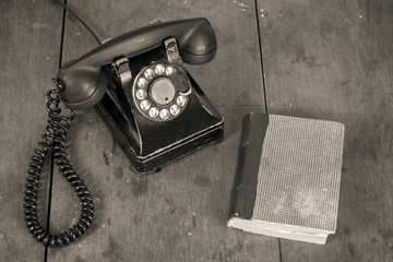 Fototapete - Old vintage phone, book on wooden table background