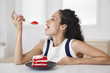 © Peter Dressel/Blend Images - Hispanic woman eating cake in kitchen