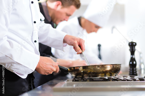 Fototapeta na wymiar Three chefs in team in hotel or restaurant kitchen