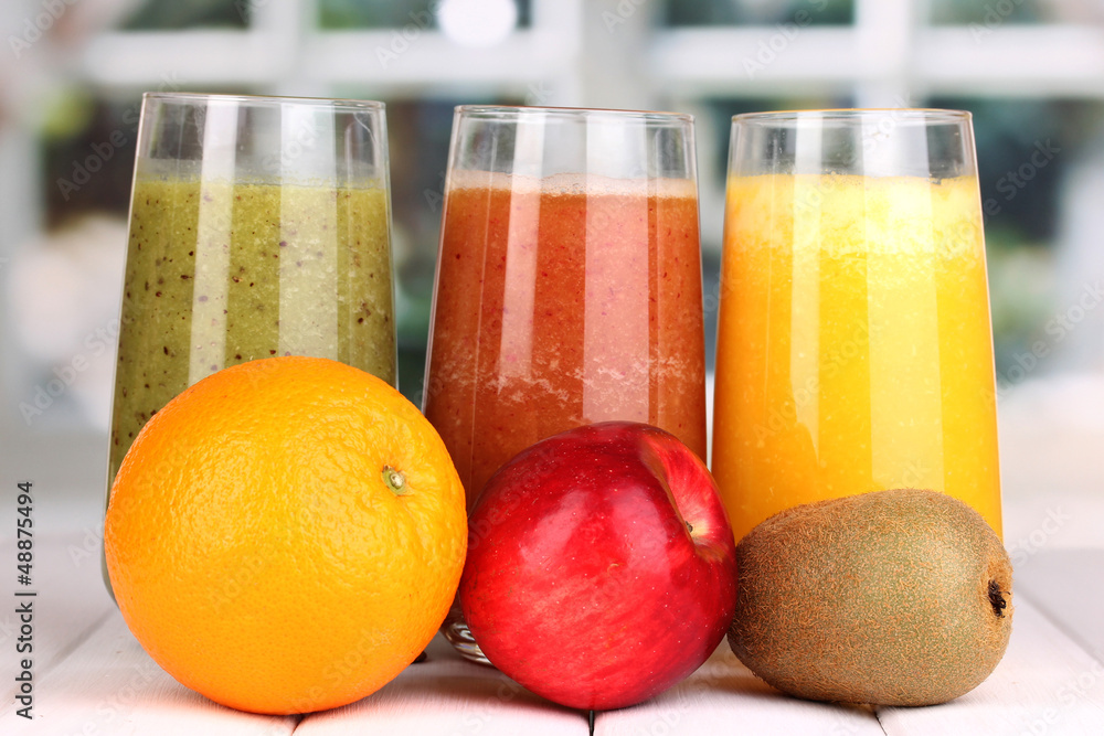 fresh fruit juices on wooden table, on window background