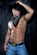 Muscular handsome man posing in a cowboy hat and jeans over the