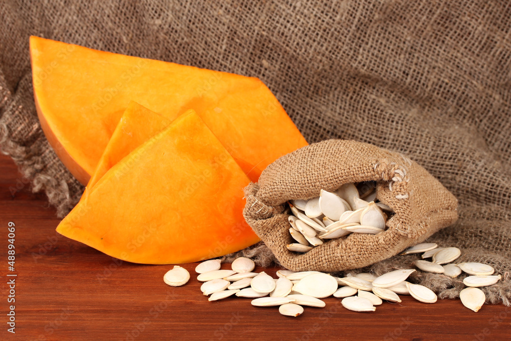 Pumpkin seeds in sack, on wooden background