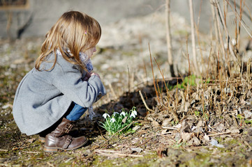 Little toddler girl touching flowers