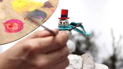 Wall Mural - man painting buttons on a snowman miniature