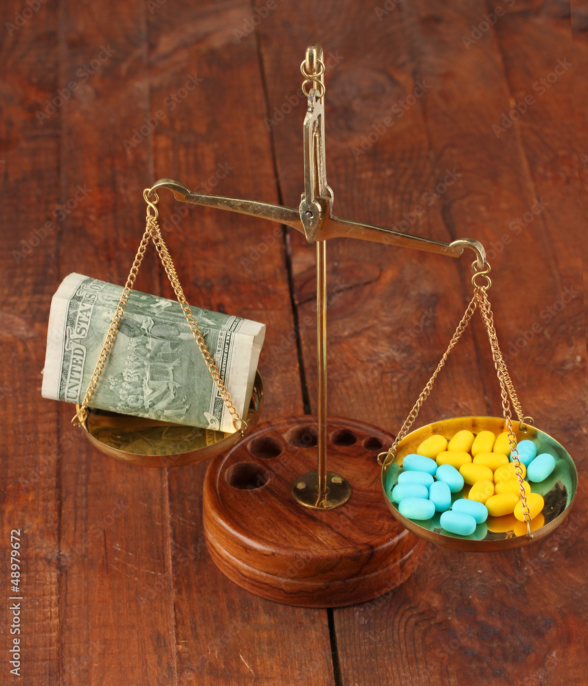 Classic scales with color pills on wooden background