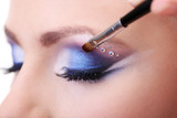 Beautiful female eyes with bright blue make-up and brush