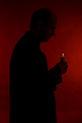 Wall Mural - Portrait of young Pastor holding candle in his hand, isolated