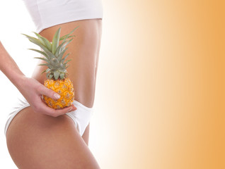 Wall Mural - Belly of a young woman in white lingerie holding a pineapple