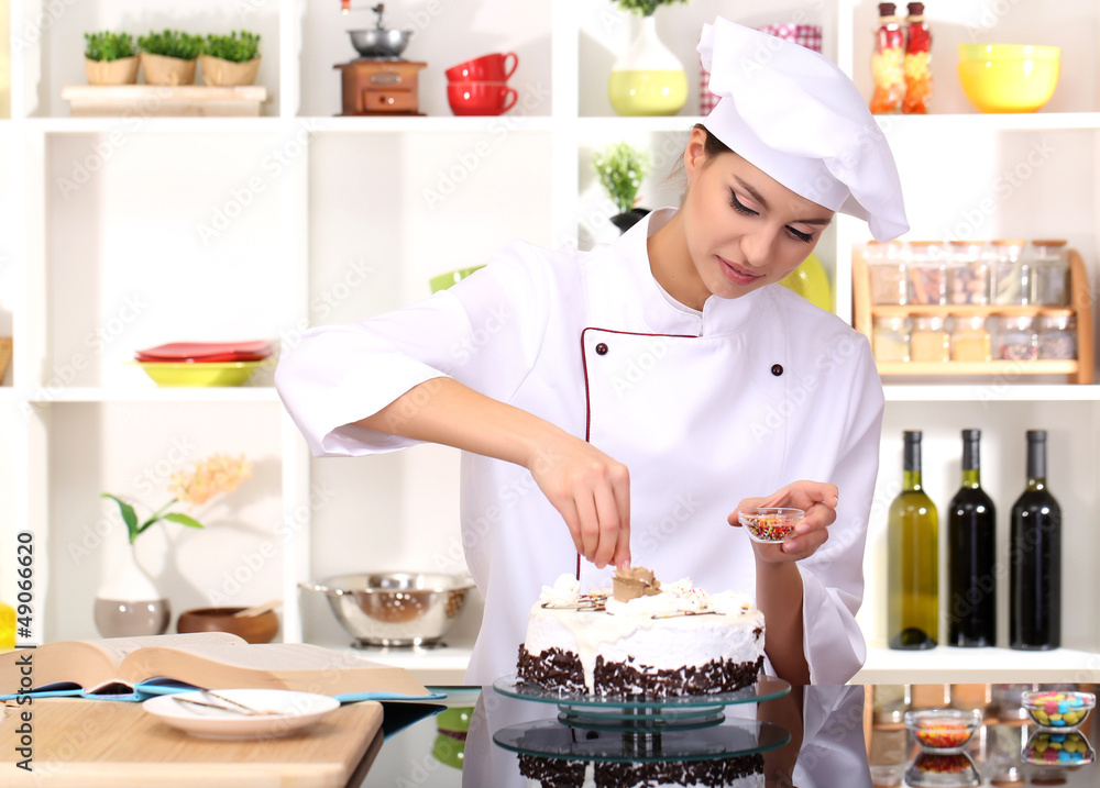Young woman chef cooking cake in kitchen