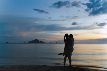 Young couple is kissing at sunset