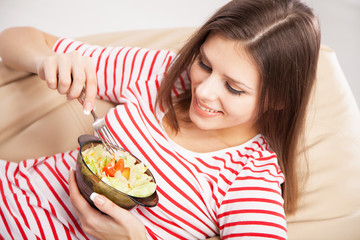 Beautiful young woman eating a salad