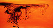 Black ink dispersing in orange water