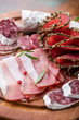 Assorted cold cuts with rosemary on chopping board
