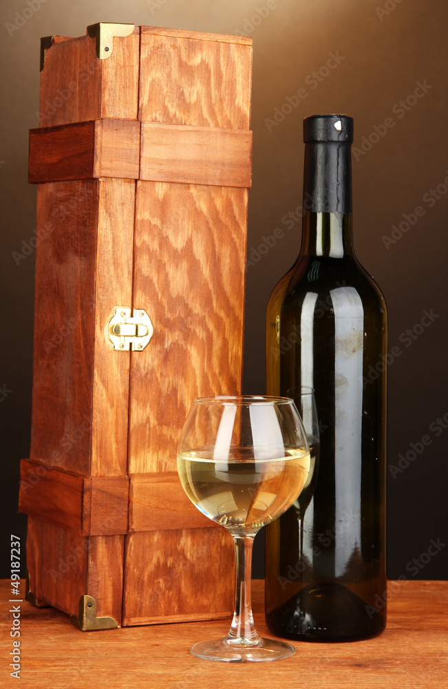 Wooden case with wine bottle on wooden table on brown