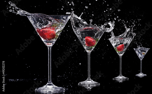 Fototapeta na wymiar Martini drinks with splashes, isolated on black background