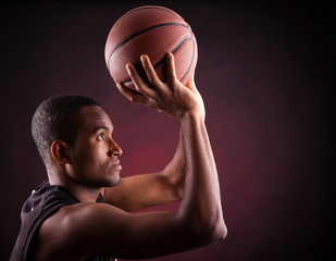 Wall Mural - Portrait of a young male basketball player against black backgr