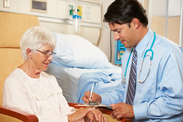 Wall Mural - Doctor Taking Notes From Senior Female Patient Seated In Chair