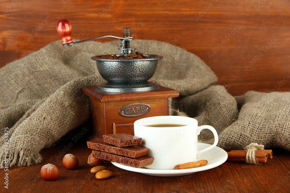 Dark chocolate, hot drink and coffee mill on wooden background