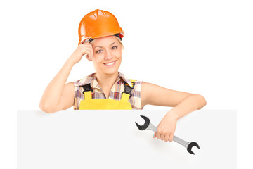 Wall Mural - A smiling female worker holding a wrench and standing behind pan