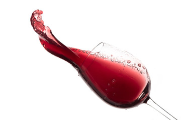 Wall Mural - red wine splashing out of a glass, isolated on white