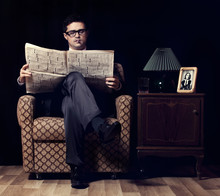 Man With Newspaper Sitting In Vintage Armchair