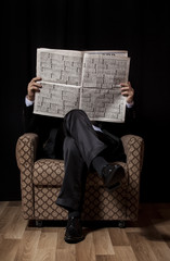 Man with newspaper sitting in vintage armchair