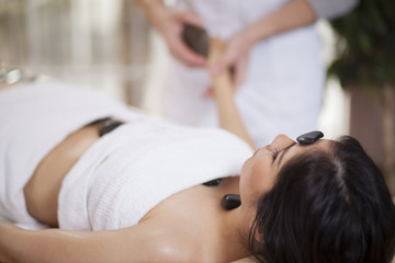 Wall Mural - Pretty young woman getting a stone massage at a spa