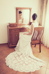 bride sitting on chair and looking through mirror