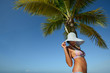 Woman in summer hat sunbathing under a palm tree on a background
