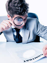 Businessman with magnifying glass reading the fineprint in a con