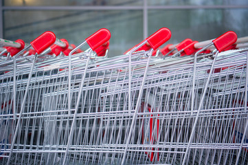 Rows of shopping carts on car park near entrance of supermarket