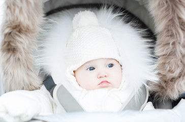 Wall Mural - Funny little baby in a warm stroller on a cold winter day