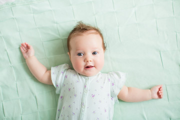 Wall Mural - Beautiful baby girl blue eyes playing on knitted mint blanket