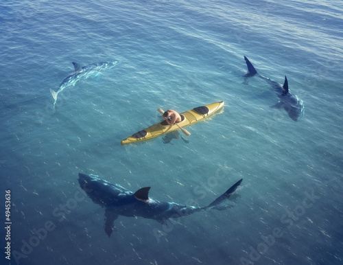 Naklejka dekoracyjna Man on a boat in the middle of the ocean surrounded by sharks.