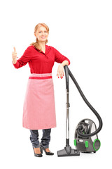 Wall Mural - Blond housewife posing on a vacuum cleaner and giving thumb up