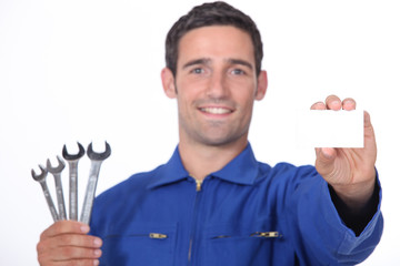 Mechanic holding selection of spanners and business card