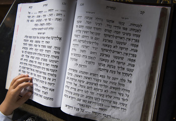 a boy's hand on a jewish bible