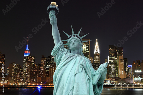 Board z aluminiowym obramowaniem Panoramę Manhattanu i Statuę Wolności w nocy