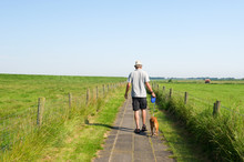 Man Walking The Dog In Summer Landscape