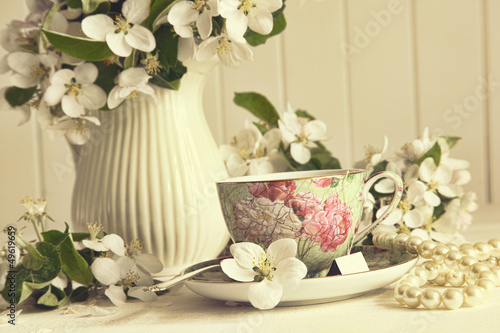 Plakat Filiżanka herbaty z kwiatami jabłoni na stole