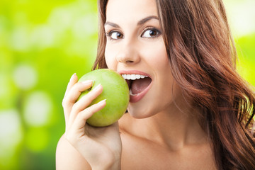 Young woman eating apple, outdoors