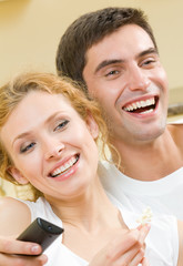 Wall Mural - Cheerful young couple watching TV together