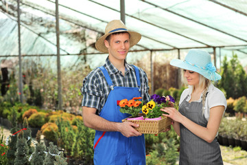 Female and male gardeners with a basket full of flower pots in a