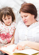 © Smailhodzic - A mother and her little daughter reading a book before sleeping