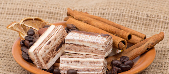 Sweets, cinnamon, nuts and coffee beans on a saucer, on burlap b