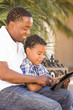 © Andy Dean - Mixed Race Father and Son Using Touch Pad Computer Tablet