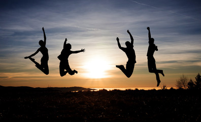 silhouette of teenagers jumping in sunset for fun