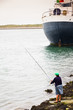 Local woman fishing near the big cargo ship